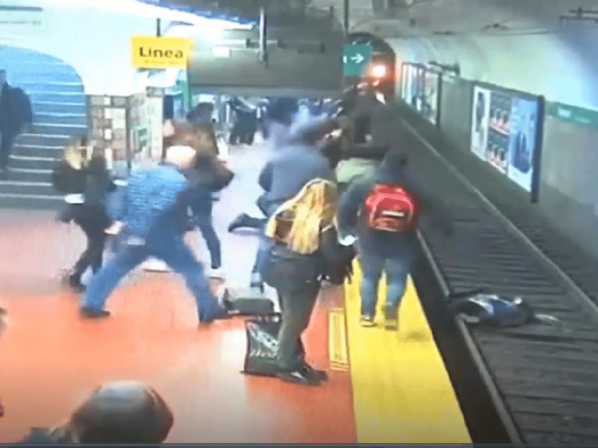 [VIDEO] Dramático momento en el que un hombre se desvanece y empuja a una mujer a las vías del tren